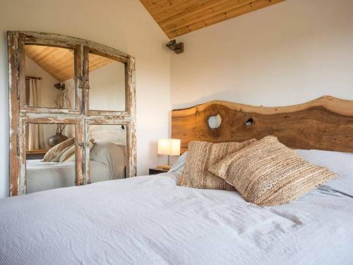 a bedroom with a bed with a wooden headboard and a mirror at Beachside chalet 3 Cormorant with access to beach in Cowes