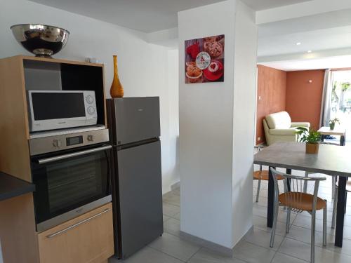 een keuken met een koelkast, een magnetron en een tafel bij L'échappée Comtoise in Baume-les-Dames