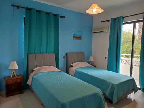 two beds in a room with blue walls at Dolphin Apartments in Faliraki