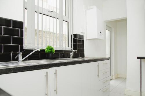 a kitchen with white cabinets and a sink and a window at Easygoing Central Oasis in Liverpool
