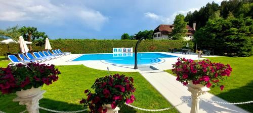 a swimming pool with chairs and flowers in a yard at Sport Manca Garni Hotel in Radovljica