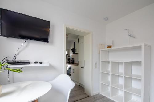 una sala de estar blanca con TV en la pared en Ferienhaus Annika in Schillig-Horumersiel mit 8 modernen Wohnungen, en Schillig