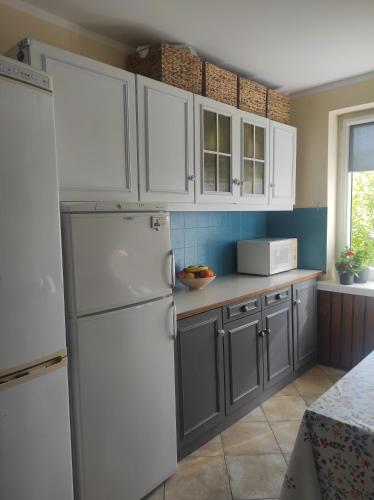uma cozinha com armários brancos e um frigorífico branco em Kwatera u Kasi em Świnoujście