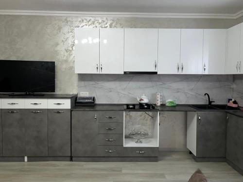 een keuken met witte kasten en een flatscreen-tv bij Roman's guest house in Garni in Garni