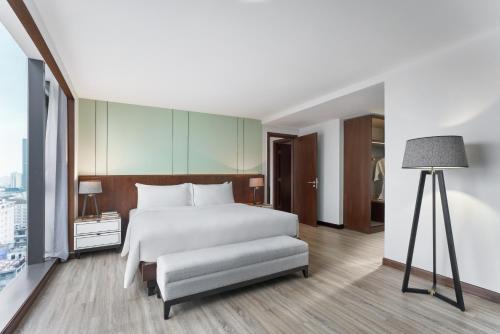 a bedroom with a white bed and a lamp at Signature by M Village Lê Thánh Tôn in Ho Chi Minh City