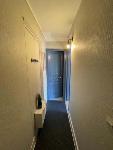 a hallway with a blue door and a table in a room at Villa Artiz in Dunkerque