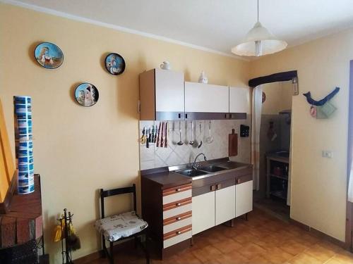 a kitchen with white cabinets and a sink at House Mare & Supramonte in Baunei