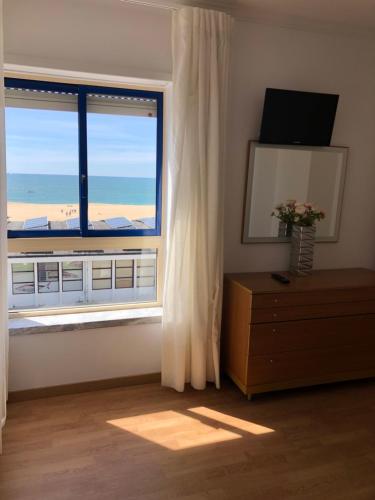a room with a large window with a view of the beach at Apartamentos 7 Saias - Centro in Nazaré