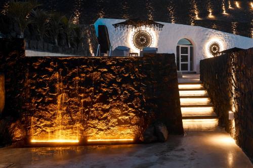 a fountain in front of a house with lights at Theano Cave Suites & Villas in Imerovigli