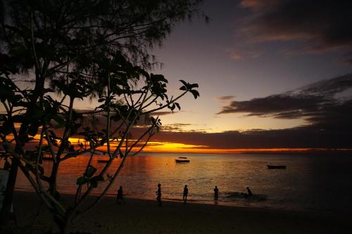 - un groupe de personnes debout sur la plage au coucher du soleil dans l'établissement Cocolala Beach House, à Nungwi