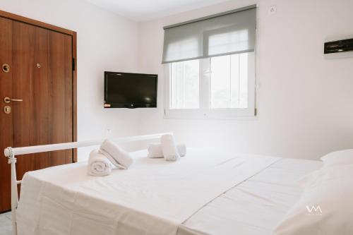 Un dormitorio blanco con una cama con toallas. en Oikies Verde III-F, en Perdika
