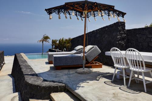 a patio with an umbrella and chairs and a pool at Theano Cave Suites & Villas in Imerovigli