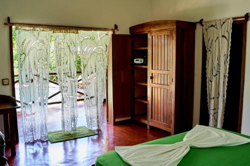 a room with a bed and a window with curtains at Villa MILENA in Nosy Be