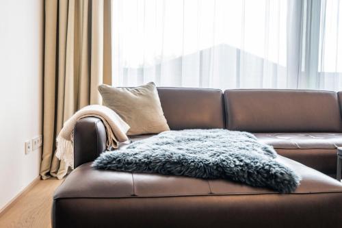 a brown leather couch with a furry blanket on it at MÖRWALD Relais & Châteaux Hotel am Wagram in Feuersbrunn