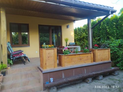 a house with a porch with two wooden chests with flowers at Dolistówka Apartamenty, pole namiotowe, balia z jacuzzi, ogród warzywny dla gości, plac zabaw dla dzieci in Goniadz