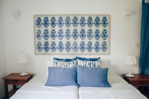 um quarto com uma cama branca e almofadas azuis em Just Like Home Casa do Castanheiro em Afife