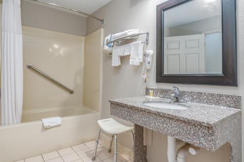 a bathroom with a sink and a mirror and a shower at Days Inn by Wyndham Coliseum Montgomery AL in Montgomery