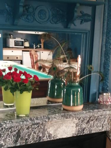 trois vases verts posés sur un comptoir avec des fleurs dans l'établissement Chambre E André Le Domaine Des Jardins De Bracquetuit, à Bracquetuit