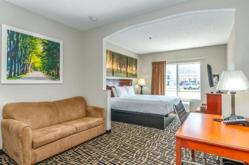a hotel room with a bed and a couch and a desk at Days Inn by Wyndham Coliseum Montgomery AL in Montgomery