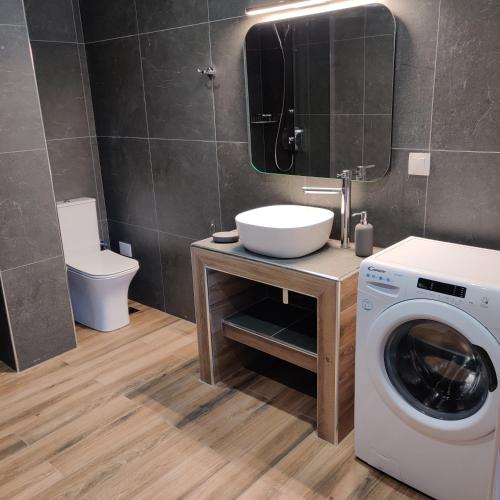ein Badezimmer mit Waschmaschine und Waschbecken in der Unterkunft Mare Monte Luxury Apartments 4 in Kassandria