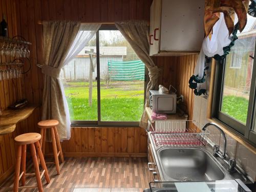eine Küche mit einem Waschbecken, einem TV und einem Fenster in der Unterkunft Alojamiento Machicura in Linares