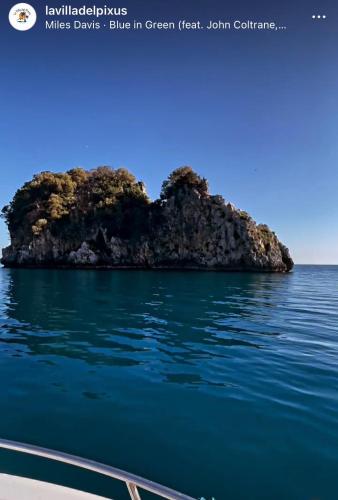 a small island in the water next to a boat at La Villa del Pixus in Pisciotta