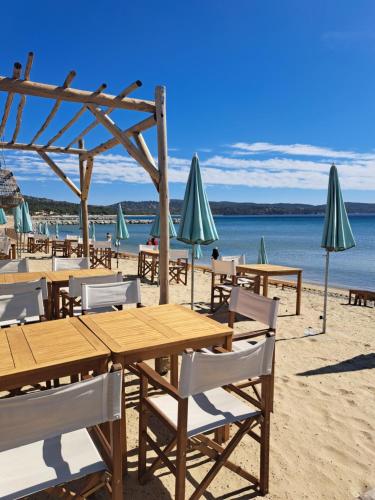 una playa con mesas, sillas y sombrillas en Location vacance vue mer 4 à 6 personnes, en Cavalaire-sur-Mer
