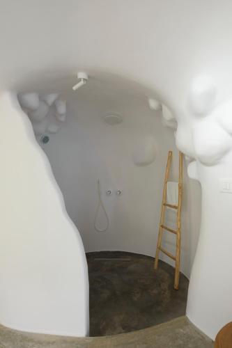 a room with a ladder and a white wall at Theano Cave Suites & Villas in Imerovigli