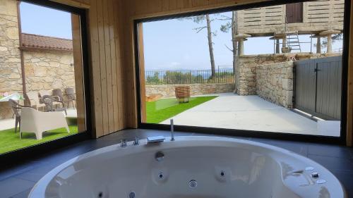 a bath tub in a room with a large window at A Casa de Elisa in Laxe