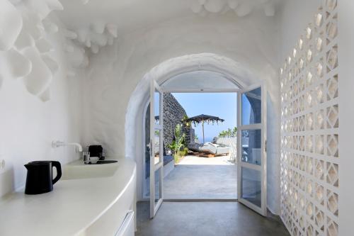 a white hallway with an archway leading to a patio at Theano Cave Suites & Villas in Imerovigli