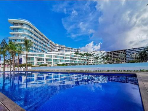 Un gran edificio con una piscina en frente. en Studio con vista al mar en Aria Ocean Nvo Vallarta, en Nuevo Vallarta 