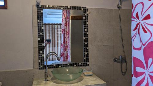 a bathroom with a bowl sink and a mirror at Hôtel chez Pat in Nosy Be