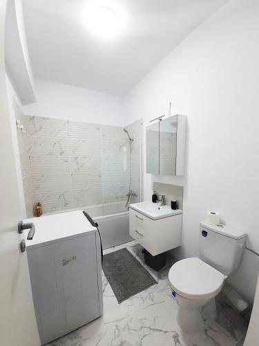 a white bathroom with a toilet and a sink at White Flat in Bucharest