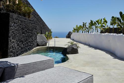 a small plunge pool in a stone wall with benches at Theano Cave Suites & Villas in Imerovigli