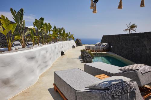 a resort with a swimming pool and chairs and the ocean at Theano Cave Suites & Villas in Imerovigli