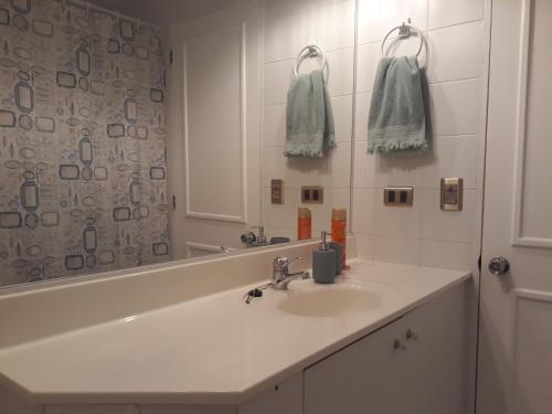 a white bathroom with a sink and a mirror at A Pasos de la Playa in Papudo