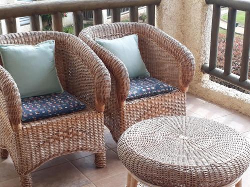 two wicker chairs and a table on a balcony at A Pasos de la Playa in Papudo