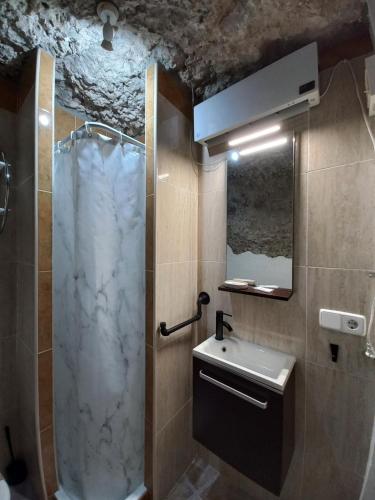 un baño con ducha y lavabo en Casa Cueva EL PORTÓN, en Alcalá del Júcar