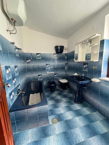 La salle de bains est pourvue de carrelage bleu, d'un lavabo et d'une baignoire. dans l'établissement Piccola Mansarda, à Parghelia