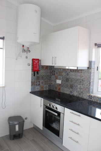 a kitchen with white cabinets and a black counter top at Casa Dom Simões in Aljezur