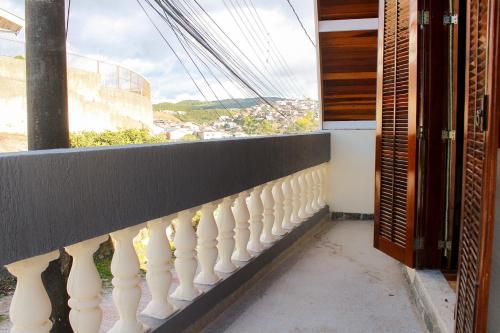 a balcony with a white railing and a window at Pousada Villa Paty - Campos do Jordão in Campos do Jordão