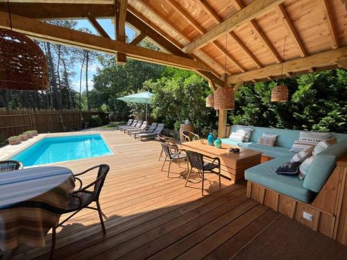 une terrasse en bois avec une piscine et une pergola en bois dans l'établissement Cabane Noa neuve- piscine chauffée, à Saint-Julien-en-Born