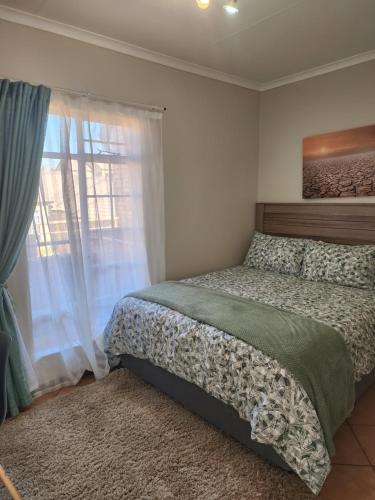 a bedroom with a bed and a window at Mooikloof Village Apartment with Solar Backup in Pretoria