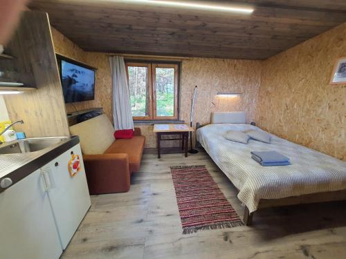 a small room with a bed and a kitchen at Skaisto saulrietu namiņš in Lembuži