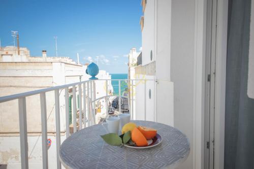 a table with a plate of fruit on a balcony at IL GELSO BIANCO Luxury apartments in Polignano a Mare