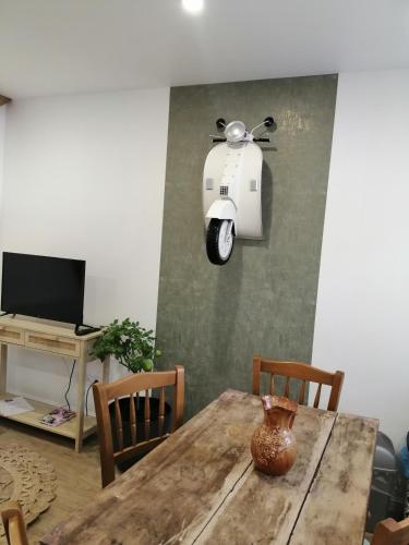 un vase sur une table avec un scooter accroché au mur dans l'établissement La romance de Laura, à Arrest