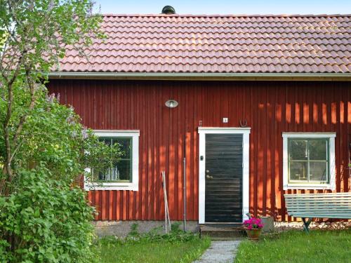 una casa roja con una puerta negra y un banco en 2 person holiday home in N SSJ, en Nässjö