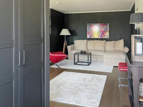 uma sala de estar com um sofá branco e uma cadeira vermelha em Holiday home Onsala IV em Onsala