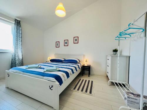ein weißes Schlafzimmer mit einem Bett und einem Fenster in der Unterkunft Apartments Elvira in Zaton