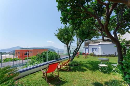 a group of chairs and a table in the grass at Poseidonia Rooms in Procida